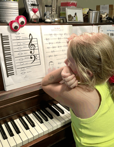 girl in lime shirt stares at a grand staff at the piano